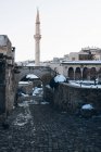 Rue vide avec pavés menant parmi les bâtiments anciens à la haute tour de minaret contre ciel bleu clair en Turquie en hiver — Photo de stock