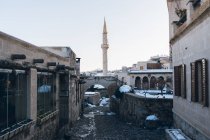 Calle vacía con adoquines que conducen entre los edificios antiguos a la torre del minarete alto contra el cielo azul claro en Turquía en invierno - foto de stock