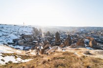 De acima do acordo famoso com edifícios de pedra antigos que sabem como casas de fadas no vale contra a colina nevada no dia ensolarado de inverno na Turquia — Fotografia de Stock