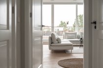 Вид из двери на гостиную со стильным диваном — стоковое фото