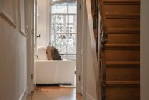 Вид из двери в гостиную со стильной мебелью и лестницей — стоковое фото