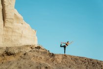 Giovane donna in abbigliamento sportivo in piedi a Natarajasana posa durante la pratica dello yoga contro la montagna durante il giorno — Foto stock