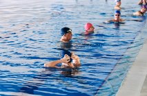 Gruppo di persone in cuffia in piscina durante le lezioni di acquagym — Foto stock