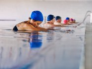 Group of people in swimming caps standing in pool during water aerobics class — Stock Photo