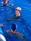 Жінки середнього віку в купальнику плавають в басейні і займаються спортом під час водної аеробіки разом — стокове фото
