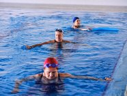 Mulheres de meia idade em trajes de banho nadando na piscina e exercitando-se durante a aeróbica aquática juntos — Fotografia de Stock