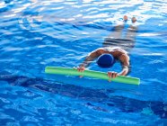 Зверху анонімної жінки, що плаває з піною локшиною в басейні під час тренування з водної аеробіки — стокове фото