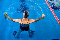 From above back view of anonymous elderly female swimmer in cap standing in water in swimming pool — Stock Photo