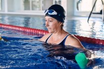 Konzentrierte reife Schwimmerin beim Wassergymnastik-Training mit Kurzhanteln im Pool — Stockfoto
