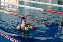 Сосредоточенная взрослая женщина-пловчиха, тренирующаяся с гантелями в бассейне во время занятий водной аэробикой — стоковое фото
