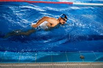Alto ángulo de ajuste de natación masculina en el estilo de arrastre en la piscina durante el entrenamiento - foto de stock