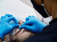Crop anonyme Schönheit Master Anwendung Wimpernlifting Schild auf dem Augenlid der Kundin während der Wimpernbehandlung im Salon — Stockfoto
