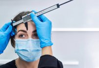 Geschnitten unkenntlich Kosmetikerin in Latex-Handschuhen mit Lineal zu messen Augenbrauen der Kundin in Schutzmaske bekommen Schönheitsoperation während Coronavirus-Pandemie — Stockfoto