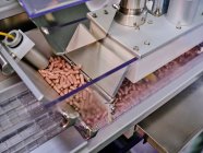 Máquina farmacêutica contemporânea com pilhas de pílulas rosa em transportador colocado em laboratório de fabricação — Fotografia de Stock