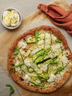 Draufsicht auf leckere Pizza mit Kürbisscheiben und Gewürzen mit frischen Rucolablättern auf Pergamentpapier auf beigem Hintergrund — Stockfoto
