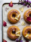 Top view of tasty donuts on cooling rack with leaves between blooming lavender sprigs on marble surface — Stock Photo