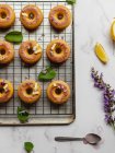 Top view of tasty donuts on cooling rack with leaves between blooming lavender sprigs on marble surface — Stock Photo