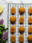 Top view of tasty madeleines on cooling rack near lavender flowers on marble surface — Stock Photo