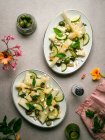 Top view of delicious melon salad with cucumbers and olives served on plate with herbs near salt shaker and napkin — Stock Photo