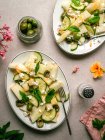 Vue de dessus de délicieuse salade de melon avec des concombres et des olives servis dans une assiette avec des herbes près de salière et serviette — Photo de stock
