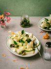 Délicieuse salade de melon aux concombres et olives servie dans une assiette avec des herbes près de salière et serviette — Photo de stock