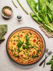 Draufsicht auf leckere Quiche mit Petersilie neben Ei und frischem Spinat mit Spargel auf dem Tisch — Stockfoto