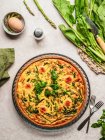 Draufsicht auf leckere Quiche mit Petersilie neben Ei und frischem Spinat mit Spargel auf dem Tisch — Stockfoto