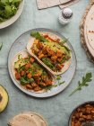 Tortillas von oben mit gebratenen Tofuwürfeln und Avocadostücken mit frischen Rucolablättern auf Tischdecke — Stockfoto