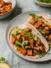 Von oben Tortillas mit gebratenen Tofuwürfeln und Avocadostücken mit frischen Rucolablättern auf Tischdecke — Stockfoto