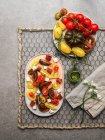 Draufsicht auf vegetarischen Tomatensalat mit Feta-Käsewürfeln, serviert auf einem Teller auf grauem Betontisch — Stockfoto