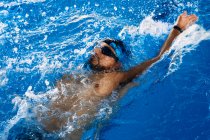 Высокий угол подтянутого мужского плавания в стиле ползания в бассейне во время тренировки — стоковое фото