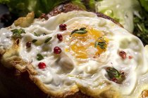 Uovo fritto su brioche servito su vassoio con lattuga fresca per appetitosa colazione su fondo nero — Foto stock