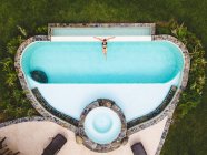 Femme vue de dessus seule dans une piscine profitant d'une journée d'été ensoleillée — Photo de stock