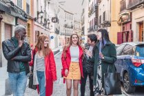 Gesellschaft fröhlicher multiethnischer Freunde in stylischer Kleidung, die am Wochenende gemeinsam auf der Straße der Stadt spazieren gehen — Stockfoto