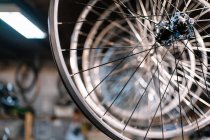 De baixo de jantes de bicicleta brilhantes de metal pendurados em rack no serviço de reparo — Fotografia de Stock