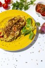 Deliziosa frittata con prezzemolo tritato su piatto contro pomodori secchi e cipolla rossa cruda su fondo bianco — Foto stock