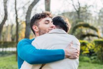 Allegro coppia LGBT di maschi abbracciando mentre in piedi nel parco nella giornata di sole — Foto stock