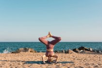 Entspanntes weibliches Balancieren in Salamba Sirsasana auf Matte beim Yoga am Strand — Stockfoto