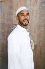 Islamic male in authentic white clothes while standing against grungy wall — Stock Photo