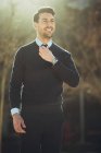 Улыбающийся бородатый мужчина-предприниматель в наручных часах с современной стрижкой, смотрящий в город в подсветке — стоковое фото