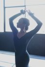 Молодая изящная женщина в черной одежде с поднятыми руками, играющая на кастаньете, исполняя традиционный испанский танец и отворачиваясь — стоковое фото
