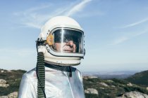 Astronauta maschio in tuta spaziale e casco in piedi su erba e pietre negli altopiani — Foto stock
