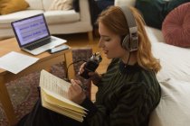 Side view of focused female radio host with mic and headphones writing in notepad while preparing for recording podcast at home — Stock Photo