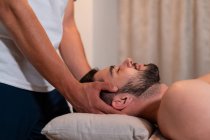 Side view of anonymous crop masseur doing Thai massage for male customer in modern spa salon — Stock Photo