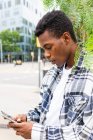 Vista lateral de mensagens masculinas afro-americanas confiantes no telefone celular enquanto está na rua da cidade — Fotografia de Stock