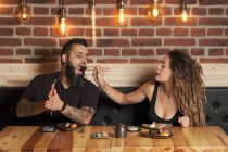 Amare coppia mangiare sushi appetitoso mentre seduto al tavolo di legno nel ristorante giapponese — Foto stock