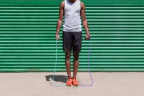 Сосредоточенные афроамериканский спортсмен скакалка во время кардио тренировки в солнечный день в городе — стоковое фото