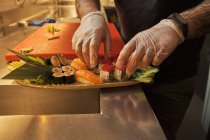 Anonyme männliche Köchin serviert Sushi auf Teller in Küche in japanischem Restaurant — Stockfoto
