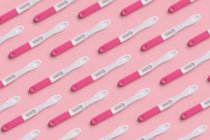 Vue du dessus du collage de test de grossesse placé en rangées paires sur fond rose — Photo de stock