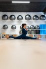 Full body side view of focused young female in activewear doing Front Splits pose and keeping hands in namaste position while practicing mindfulness during yoga class in studio — Stock Photo